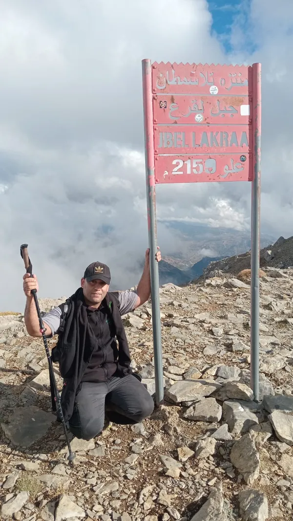 Le guide de montagne Imad Ben Yahya au panneau du sommet du Jbel Lakraa, 2159 m