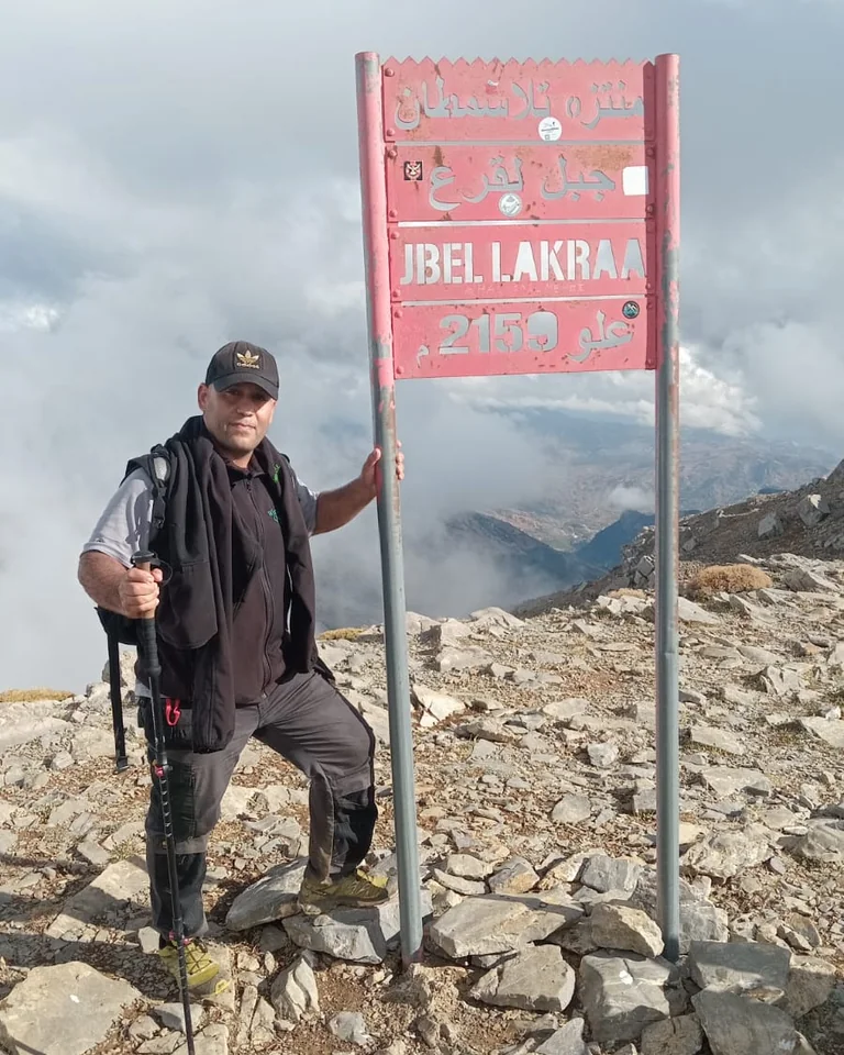 Le guide de montagne Imad Ben Yahya au panneau du sommet du Jbel Lakraa, 2159 m